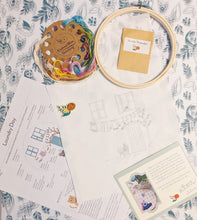 Load image into Gallery viewer, Kit contents: embroidery threads organized on a card, bamboo embroidery hoop, needle threader, magnetic needle minder (the orange flower!), preprinted 100% cotton fabric, instruction sheet - with link to online support content for more details on how to stitch everything as well as a recommended stitching order, and a thank you card!